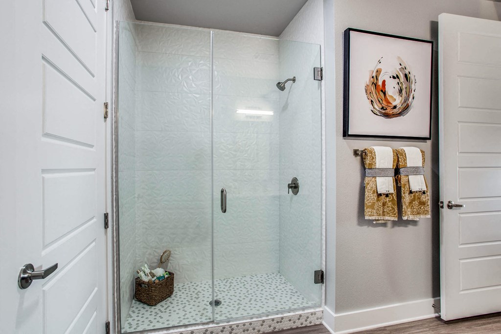the shower in the master bathroom has a glass door and a tiled floor