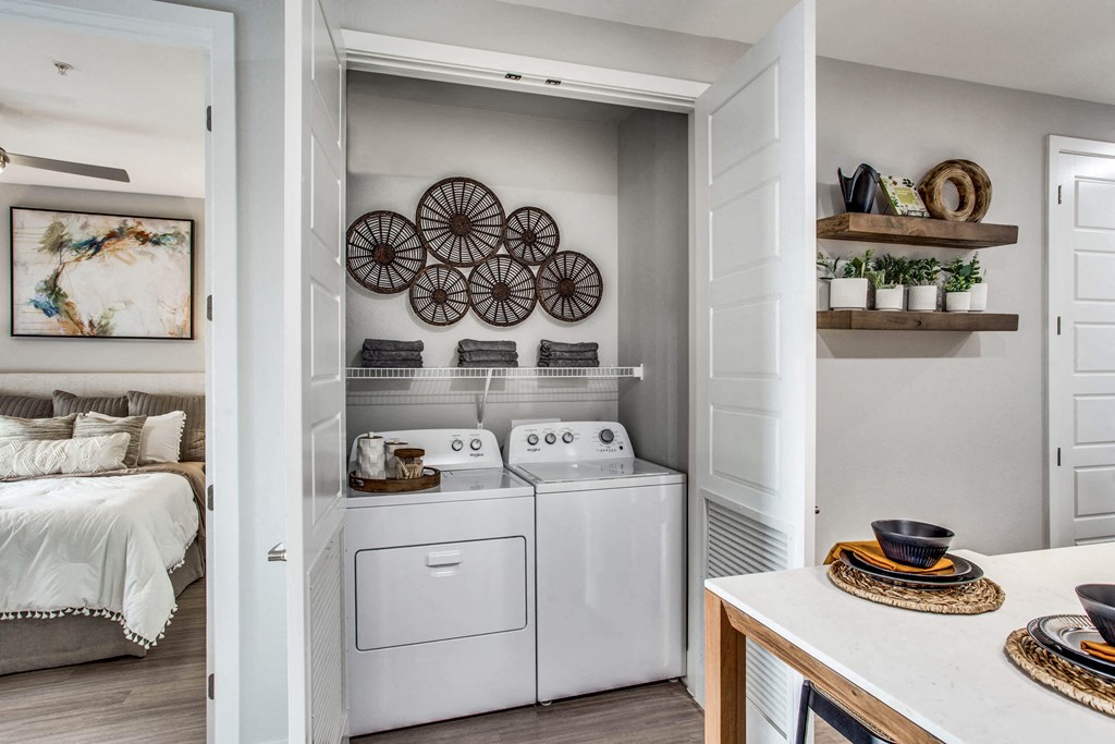 a white washer and dryer in a laundry room with a bed