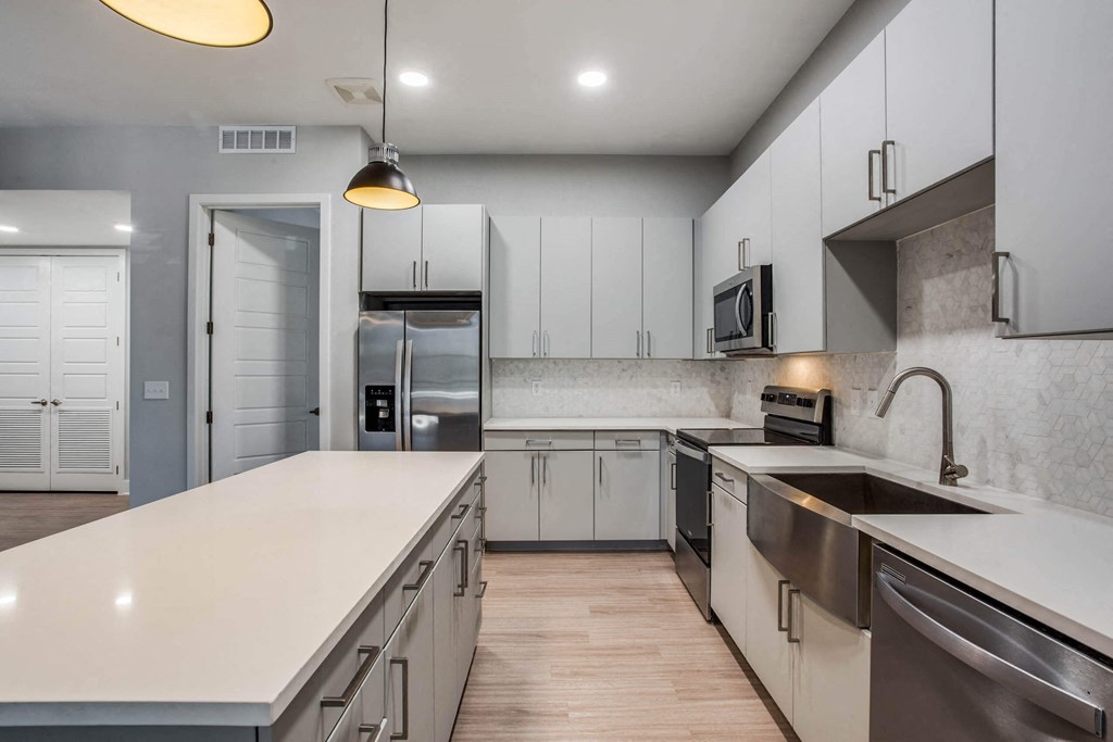 a large kitchen with white counters and stainless steel appliances