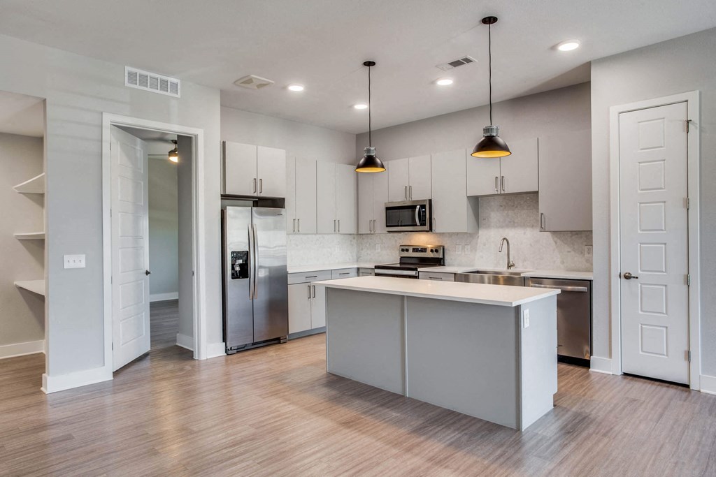 an empty kitchen with white cabinets and a stainless steel refrigerator