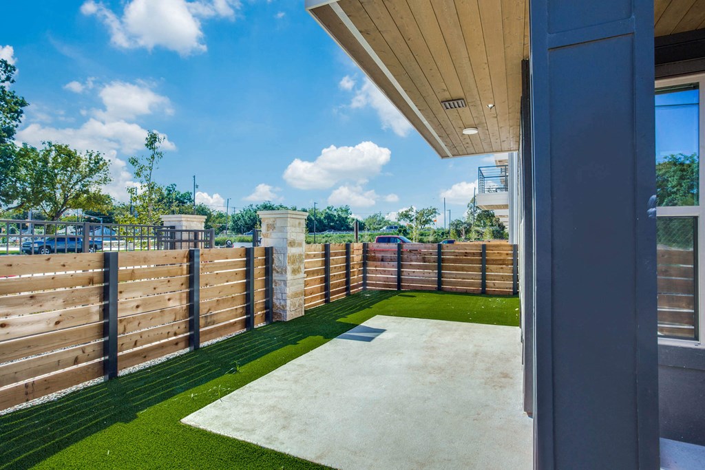 a yard with a fence and grass and a view of a parking lot