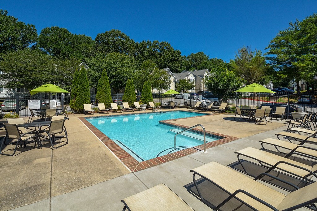 a swimming pool with chairs and umbrellas at the resort on a sunny day