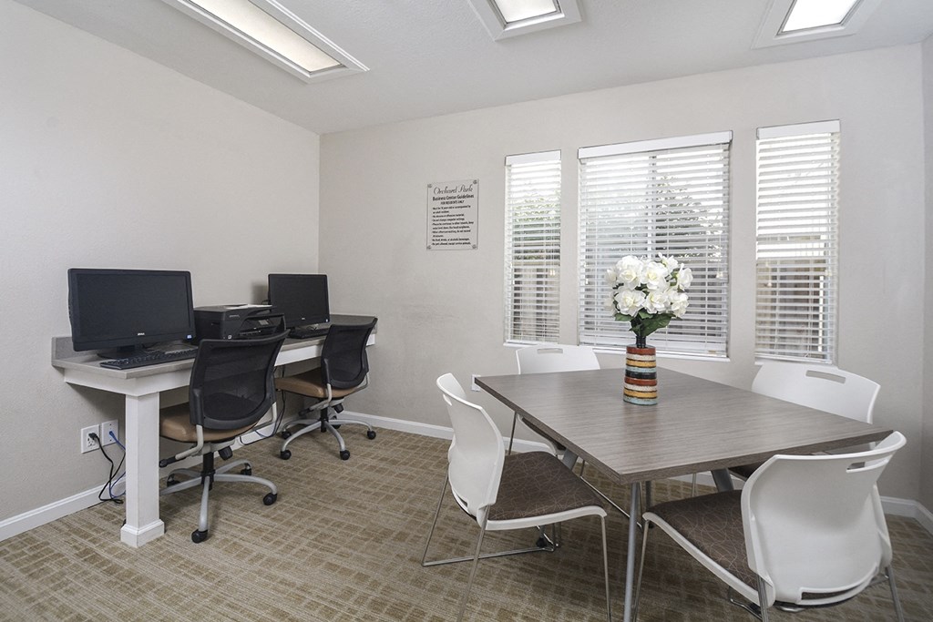 a conference room with three computers and a table and chairs