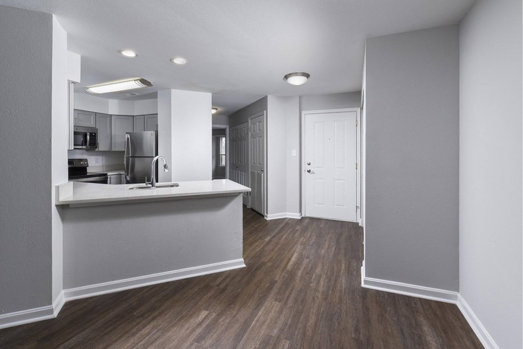 an empty apartment with a kitchen and a door to a hallway