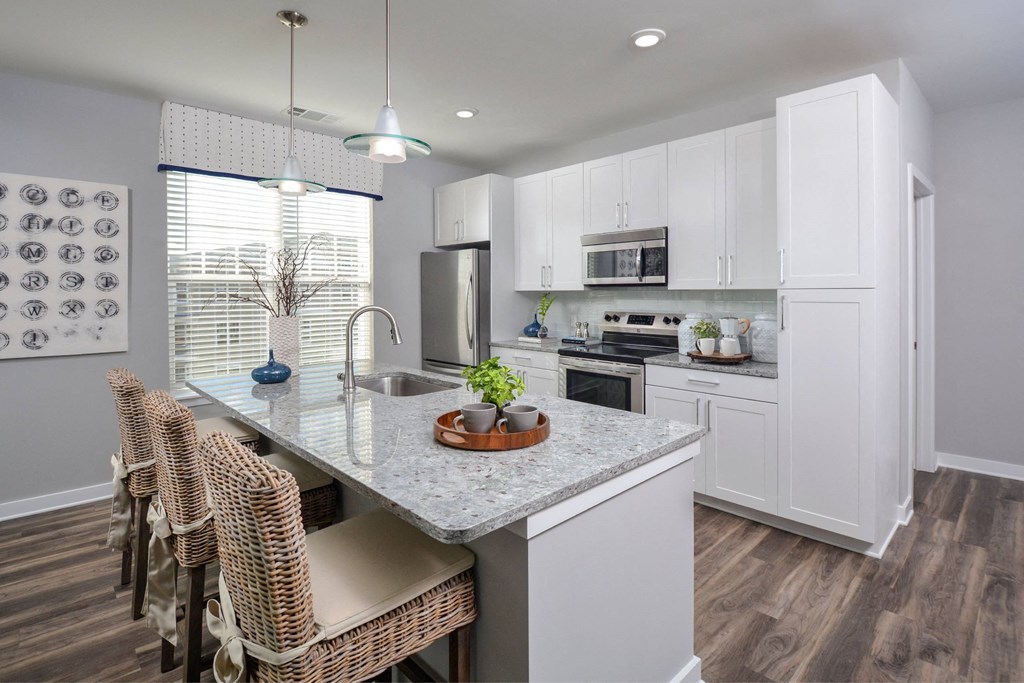 a kitchen with white cabinets and a marble counter top