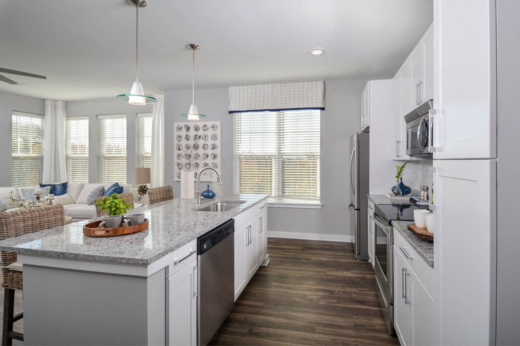 a kitchen with white cabinets and a marble counter top