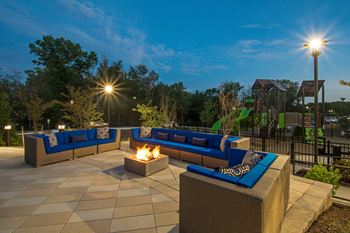 a patio with couches and a fire pit at night