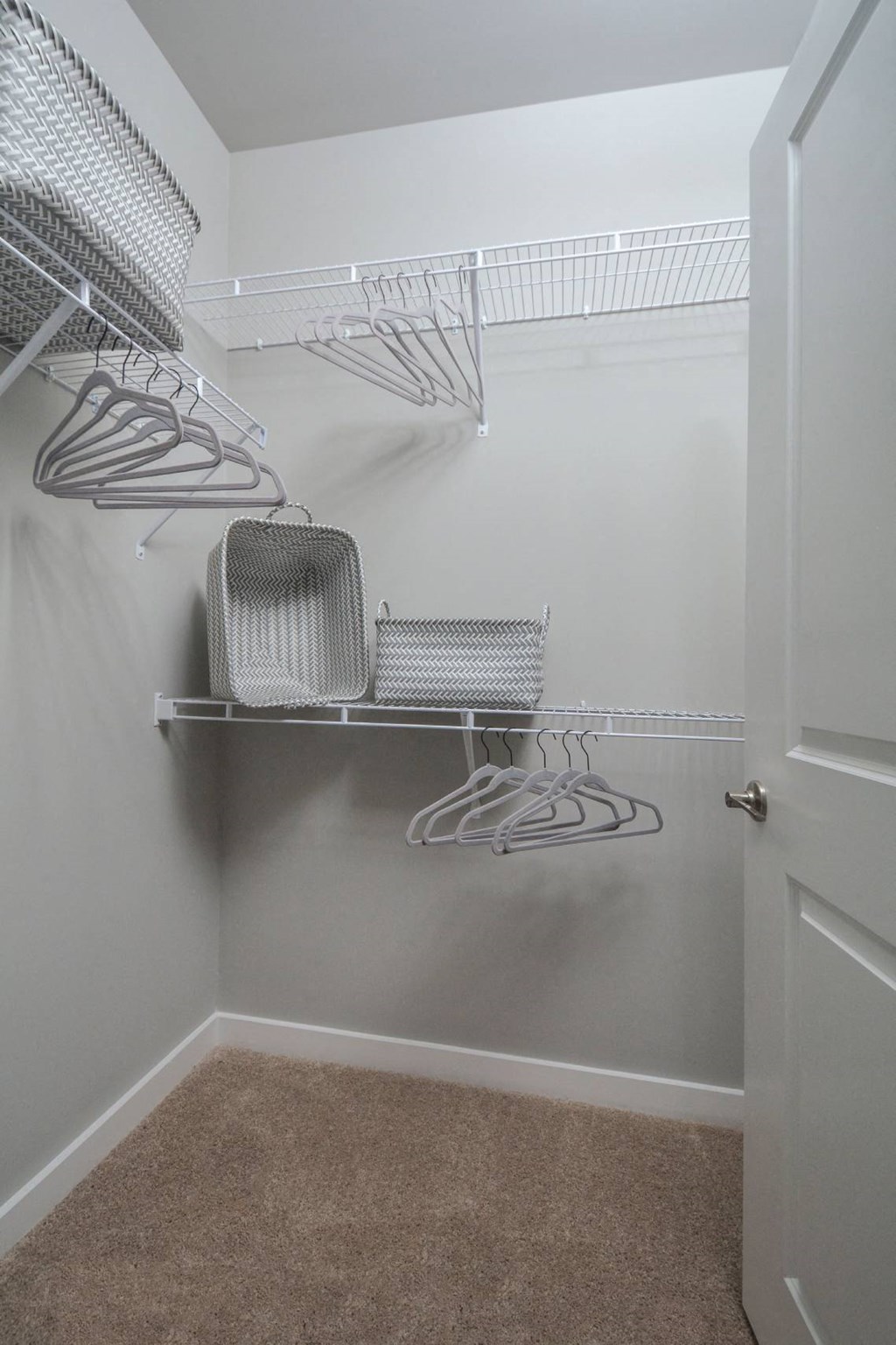a walk in closet with wire baskets on the wall