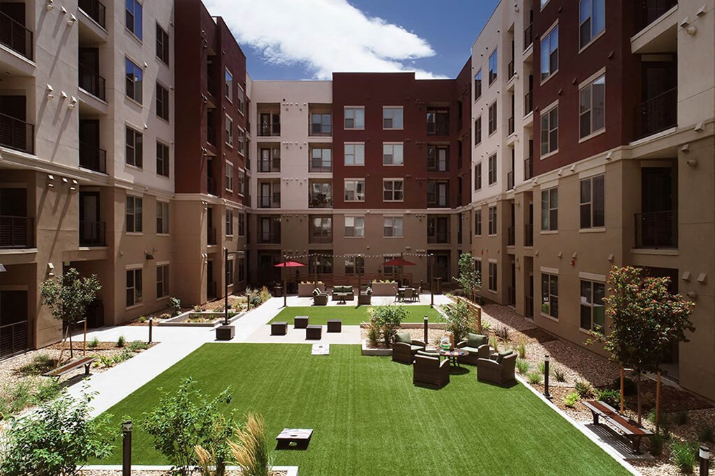a courtyard with a green lawn in the middle of an apartment building