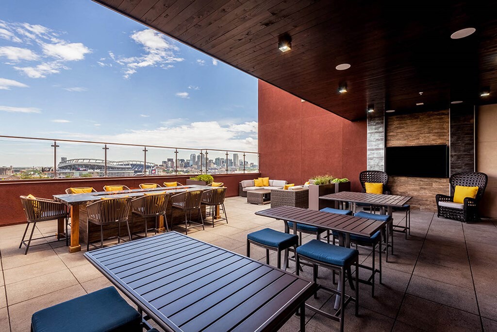 a rooftop patio with tables and chairs and a view of the city