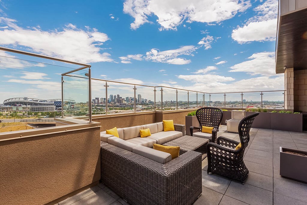 a balcony with a view of a city and a patio with furniture