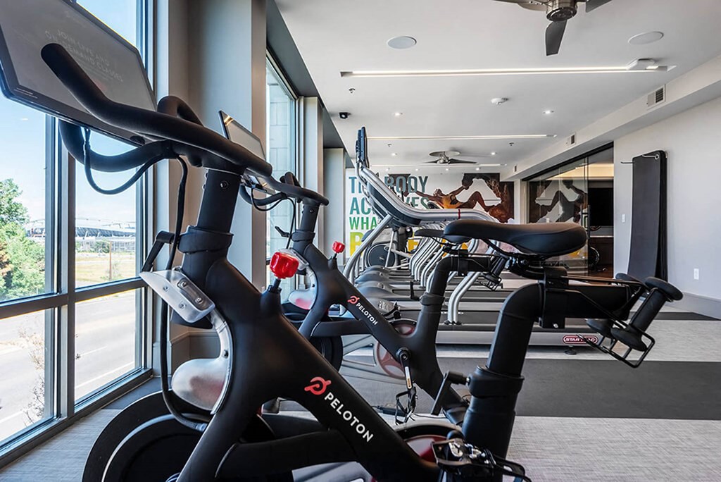 a gym with several bikes in a room next to a window
