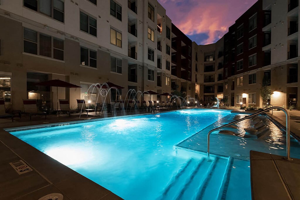 a swimming pool at night in front of an apartment building
