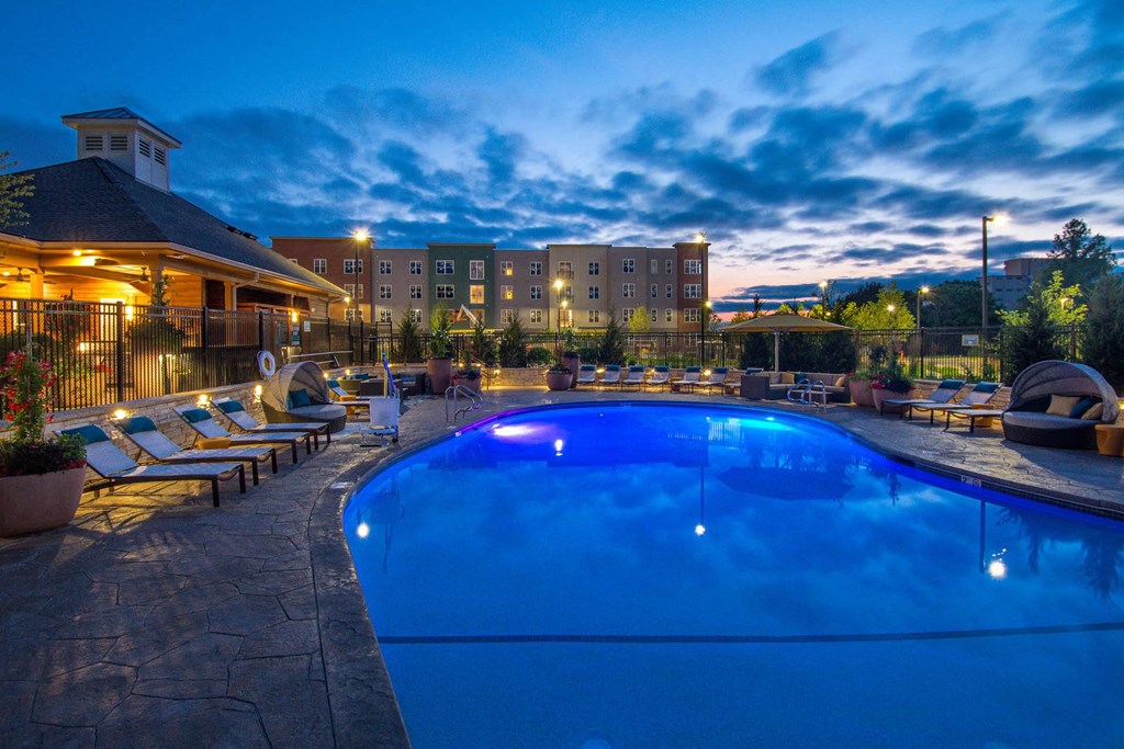 a swimming pool at night with a hotel in the background