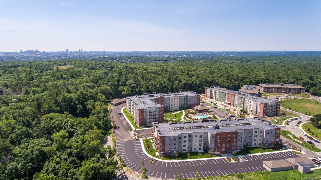 an aerial view of an apartment complex with trees and a parking lot