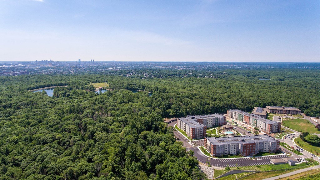 an aerial view of an apartment complex with trees and a city in the distance