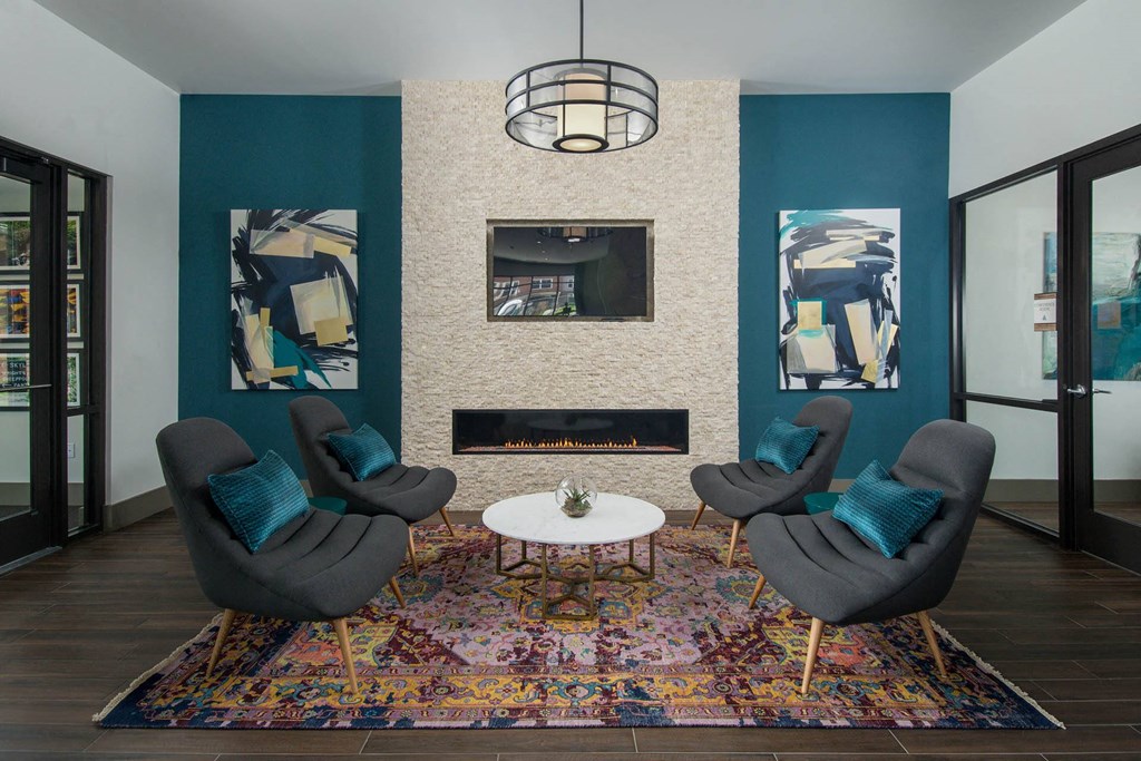 Resident lounge at Alta Clara apartments in Stoneham, MA, featuring wood grain flooring and a fireplace.