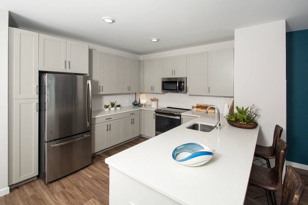 a white kitchen with stainless steel appliances and a white counter top