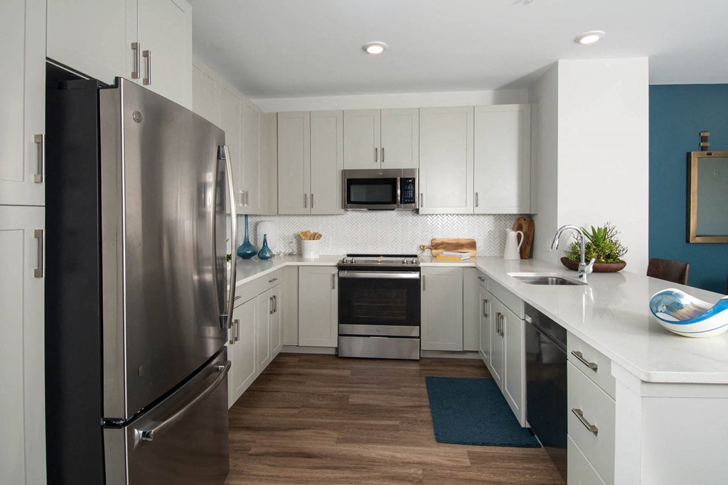 Model kitchen at Alta Clara apartments in Stoneham, MA, featuring white countertops and stainless steel appliances.