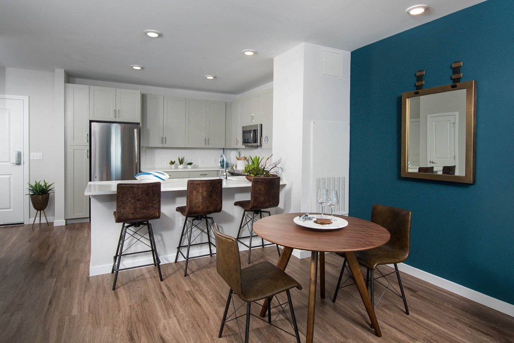 Model kitchen and dining room at Alta Clara apartments in Stoneham, MA, featuring wood grain flooring.
