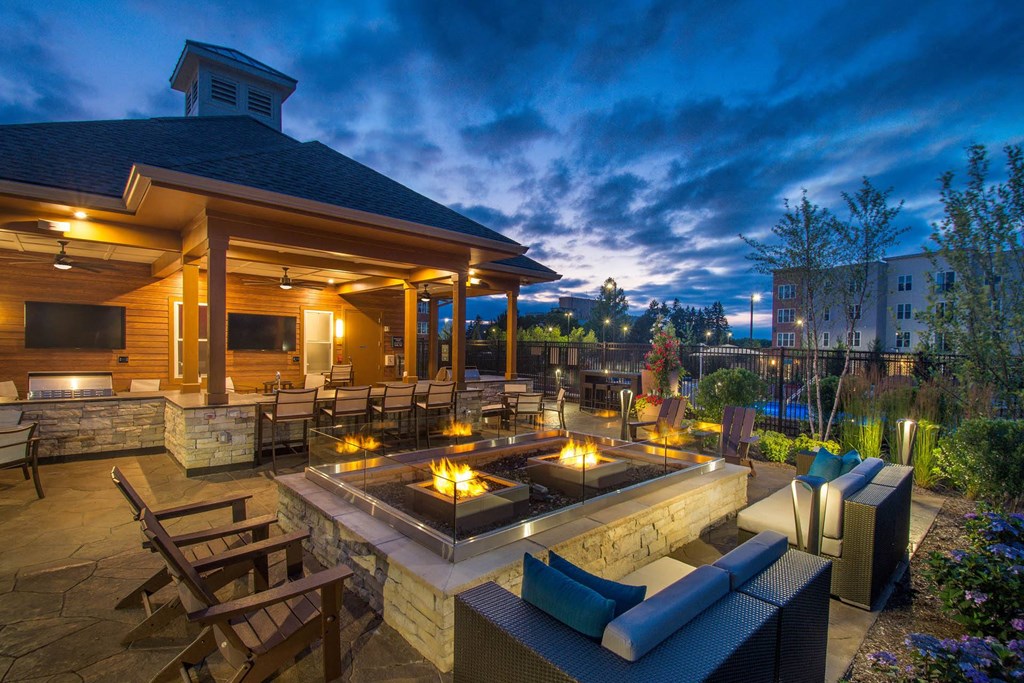 a patio with a seating area and a fire pit at night