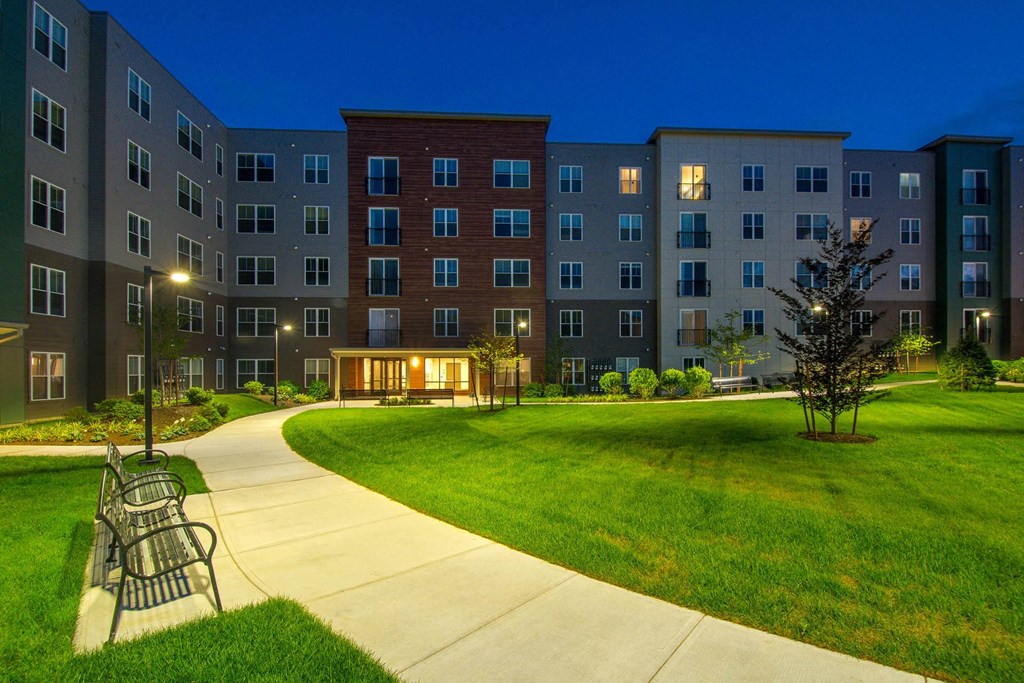 a park with a bench and an apartment building at night