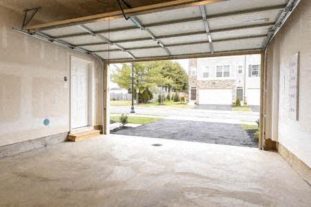 an empty garage with the door open to the street