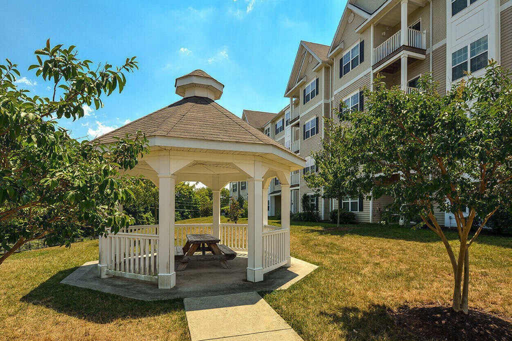 a gazebo with a picnic table in front of an apartment building