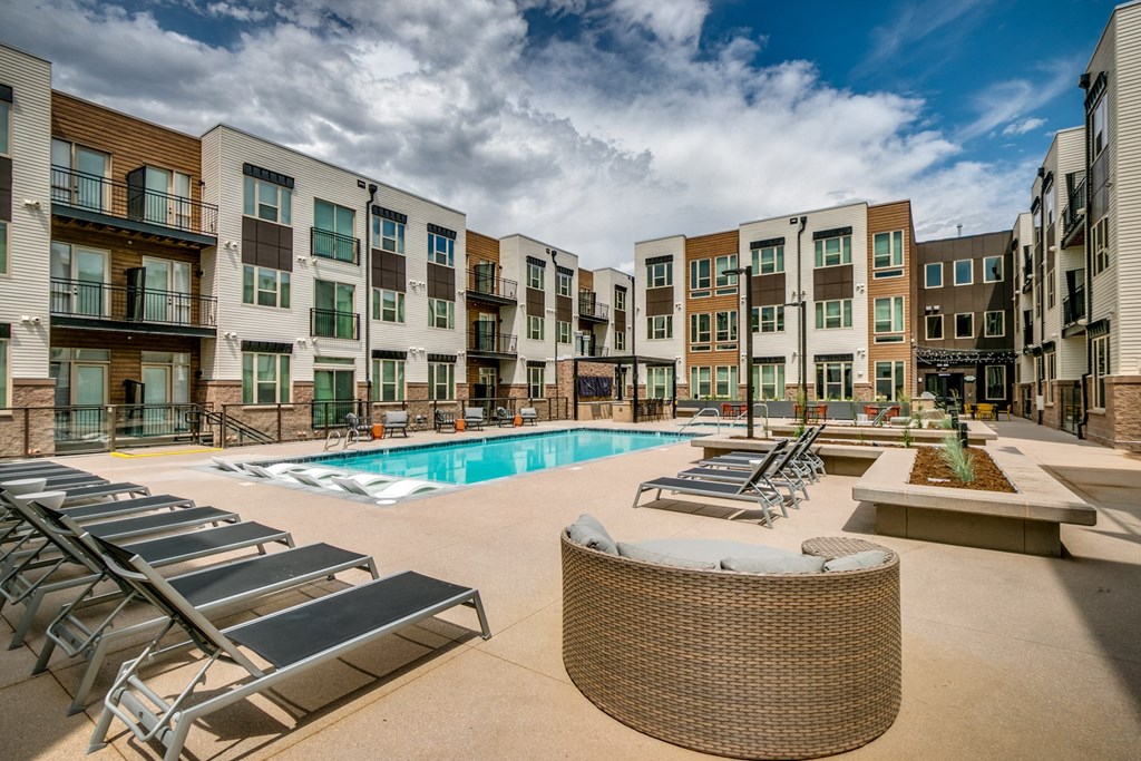an outdoor pool with lounge chairs at an apartment building