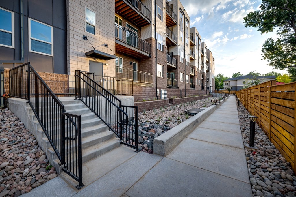 redesigned sidewalk in front of apartments with stairs and rock landscaping