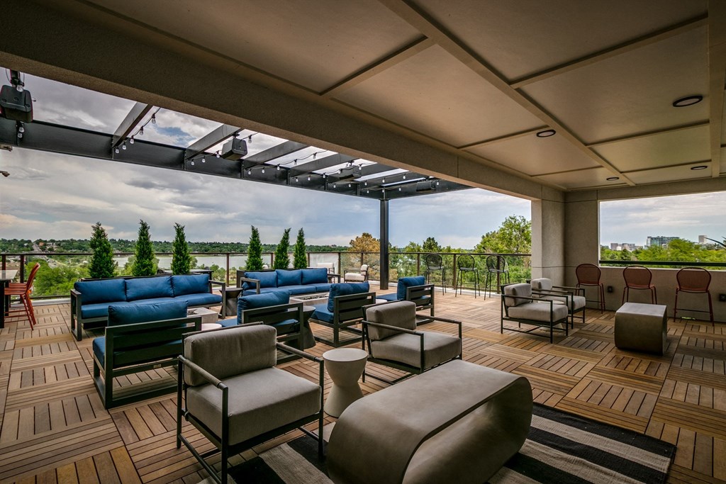 a lounge area with couches and chairs on a deck overlooking a river