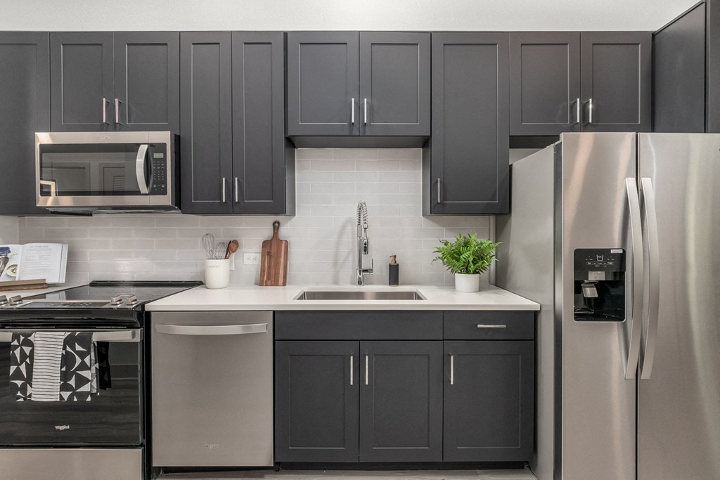 a kitchen with black and white cabinets and stainless steel appliances