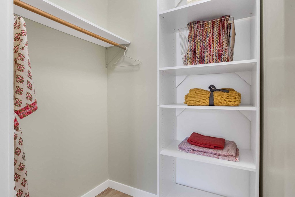 a walk in closet with shelves and a towel