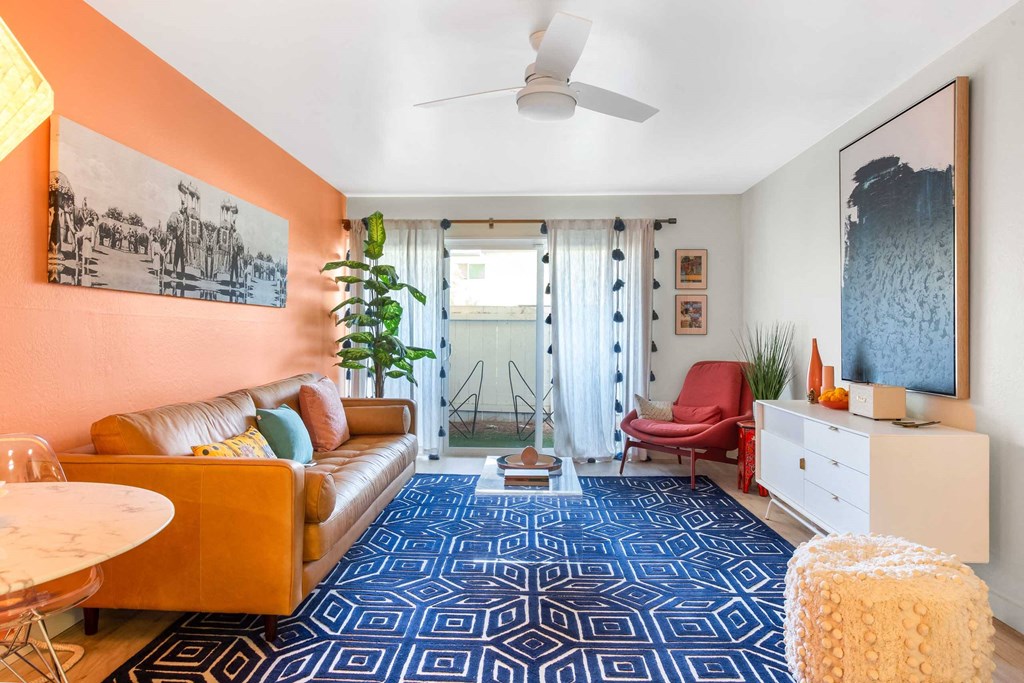 a living room with a couch and a table and a door to a balcony