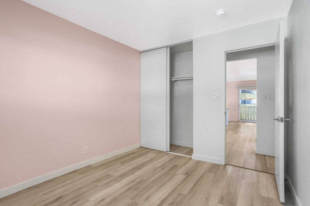 a bedroom with pink walls and a door to a closet