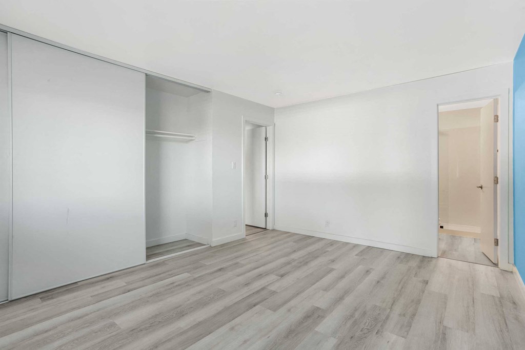 an empty room with white walls and wood floors
