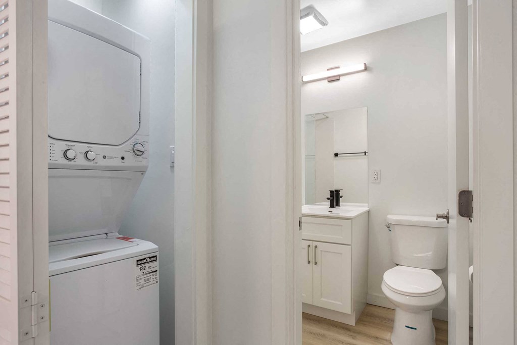 a bathroom with a washer and dryer and a toilet
