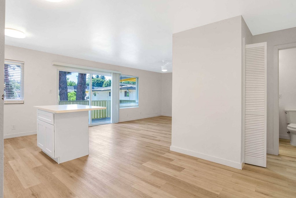 a living room with a kitchen and a door to a balcony