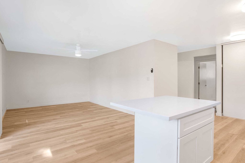 an empty living room and kitchen with a white counter top