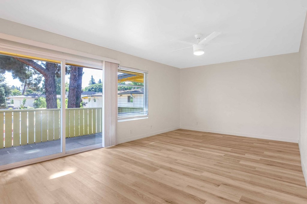 an empty living room with a sliding glass door to a balcony