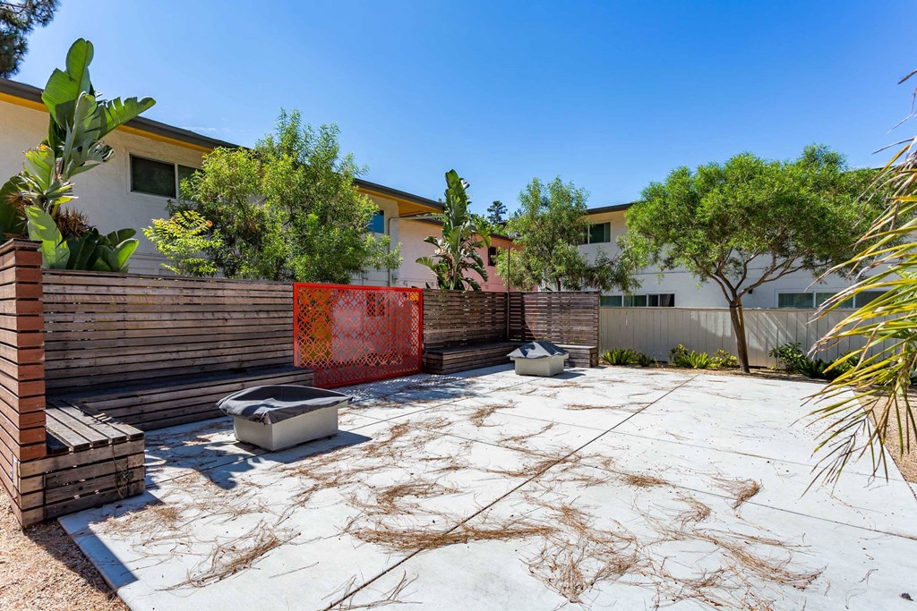 a patio with a fence and two toilets in front of a house