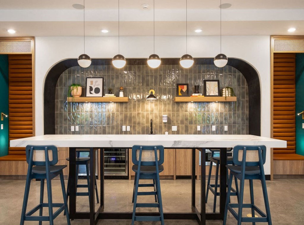 a large white bar with blue stools in front of a tile wall