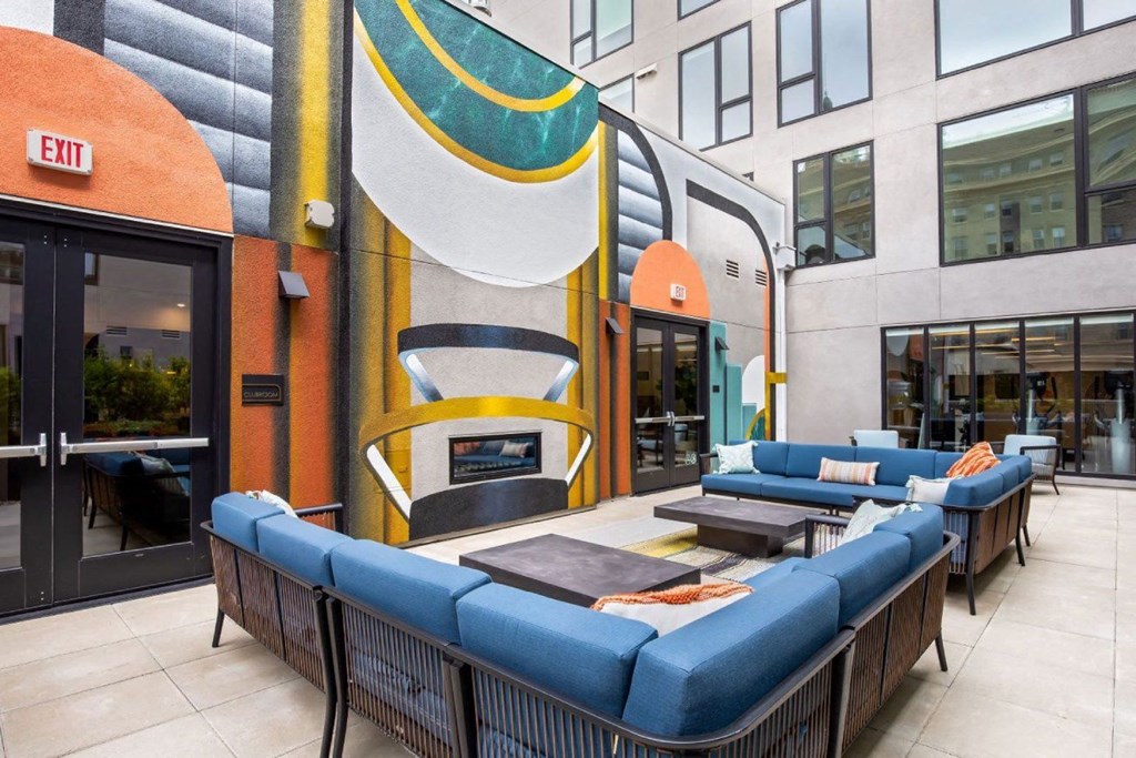 a patio with couches and tables in front of a building