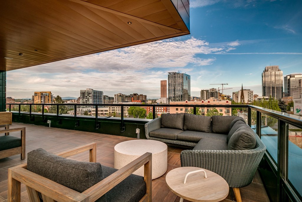 a balcony with a view of the city and a couch and tables