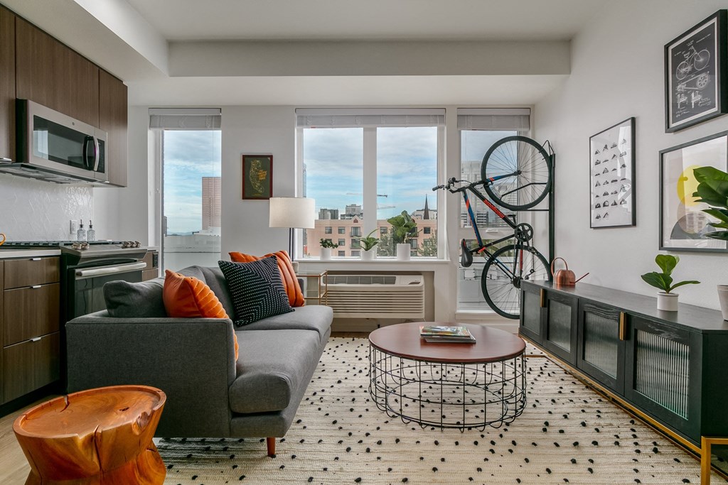 a living room with a couch and a kitchen with a bike on the wall