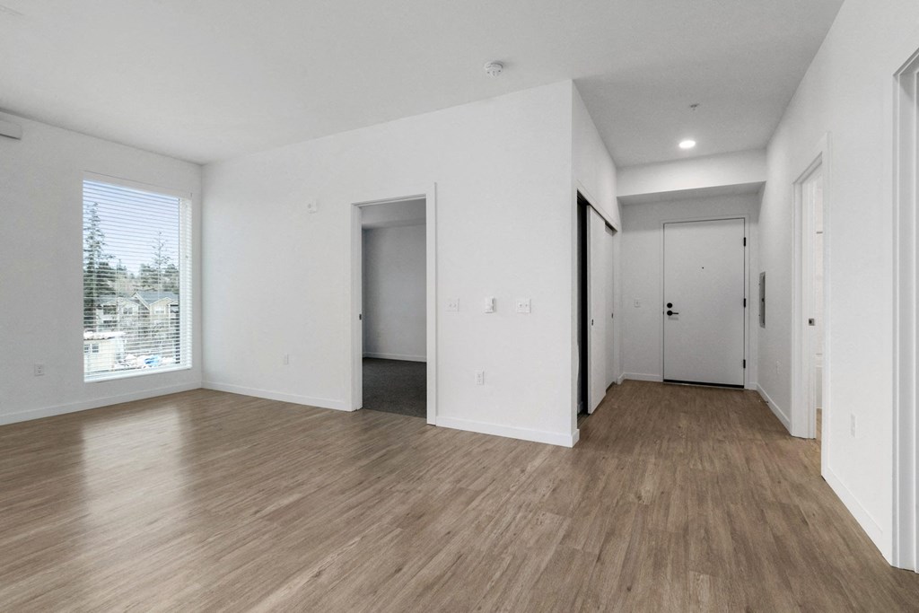 the living room of an apartment with white walls and wood floors