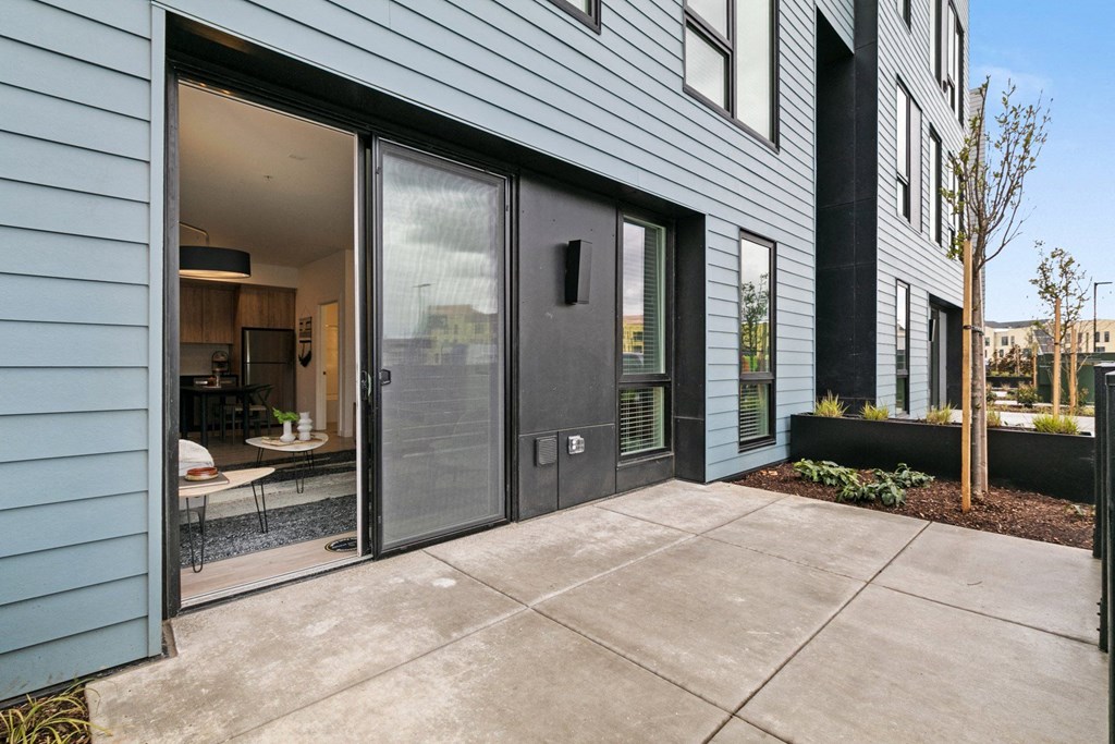 a patio in front of a blue house with glass doors