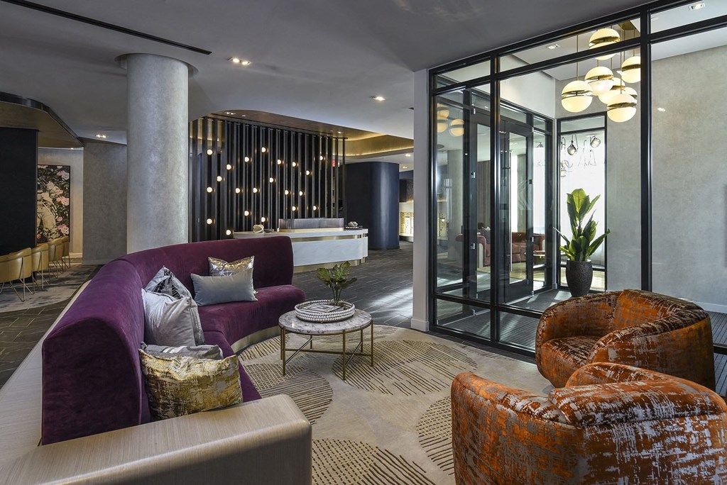 a living room with a purple couch and chairs and a large glass door