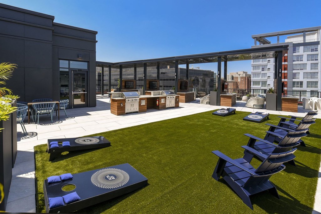 a roof top patio with lounge chairs and a barbecue
