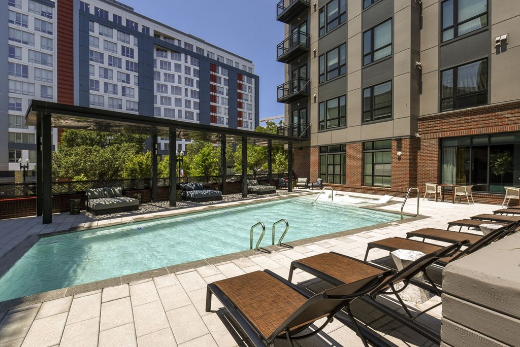 a swimming pool at an apartment building with a pool and lounge chairs